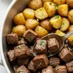Plated garlic steak bites and potatoes with glossy garlic butter and crisp edges ready to eat
