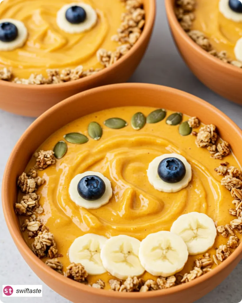 Jack-O-Lantern Smoothie Bowls ready to serve with fruit faces